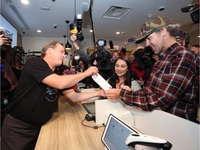 Canopy Growth CEO Bruce Linton, left to right, provides the receipt for the first legal cannabis for recreation use sold in Canada to Nikki Rose and Ian Power at the Tweed shop on Water Street in St. John's N.L. at 12:01 am NDT on Wednesday October 17, 2018.