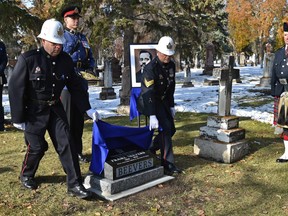 Sgt. Cliff Reimer, left, and retired Sgt. Darren Zimmerman, dressed in period clothing, unveil a cemetery monument to Const. Frank Beevers, the first Edmonton police officer killed in the line of duty, at the Edmonton Cemetery on Thursday, Oct. 11, 2018.