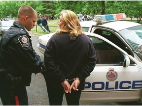 EDMONTON JOURNAL JULY 1, 1999: A constable goes through this lady s pocket before placing her into the cruiser after she was arrested for smoking pot at a cannibis rally in an Edmonton park on Canada Day. Photo by ED KAISER/Edmonton Journal.