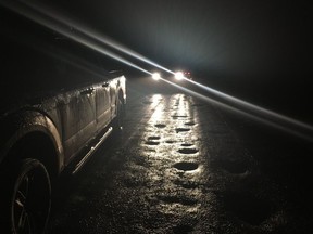 On a dark road in the middle of eastern Alberta, an RCMP truck is highlighted by the headlights of another RCMP vehicle on Oct. 11, 2018.