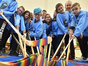 Former Edmonton Oilers captain Andrew Ference, looking over from the back, taught Lauderdale School students how to tape hockey sticks he brought to the Free Footie program on Thursday, Oct. 4, 2018.