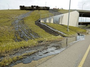 A semi tanker trailer detached from the truck and flipped over a guard rail on the Anthony Henday Drive overpass to Calgary Trail on Monday, Oct. 1, 2018. The truck was carrying 37,500 litres of hot liquid asphalt, which spilled down the embankment and into a provincial storm sewer system. The driver was not injured.