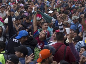 Thousands of Honduran migrants look up at a helicopter as they wait on the border between Guatemala and Mexico, in Tecun Uman, Guatemala, Friday, Oct. 19, 2018. Members of a 3,000-strong migrant caravan have massed in this Guatemalan border town across the muddy Suchiate River from Mexico, as U.S. President Donald Trump threatens retaliation if they continue toward the United States.