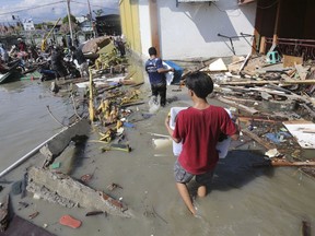 People carry items from a shopping mall badly damaged by a massive earthquake and tsunami in Palu, Central Sulawesi, Indonesia, Sunday, Sept. 30, 2018. Rescuers were scrambling Sunday to try to find trapped victims in collapsed buildings where voices could be heard screaming for help after a massive earthquake in Indonesia spawned a deadly tsunami two days ago.
