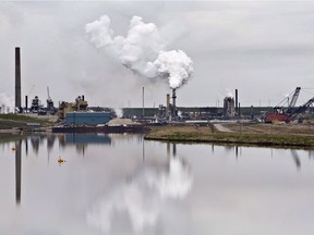 The Syncrude oil sands extraction facility is reflected in a tailings pond near the city of Fort McMurray, Alberta on Sunday June 1, 2014. The Alberta Energy Regulator has approved a tailings pond management plan for oilsands miner Syncrude Canada despite its reliance on a remediation method that isn't endorsed by the agency.