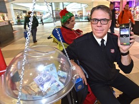 Maj. Al Hoeft of the Salvation Army Kettle Campaign holds one of 15 point of sale terminals that are now accepting donations by debit and credit card. Volunteer Shannon Kidner, back, is ringing the bells in City Centre Mall on Monday, Nov. 26, 2018 in the campaign that goes until Dec. 24 with a goal of raising $550,000 in Edmonton.