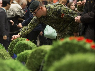 A member of the Canadian military places a poppy on a wreath during the Remembrance Day Service at the University of Alberta's Van Vliet Centre, in Edmonton Sunday Nov. 11, 2018.