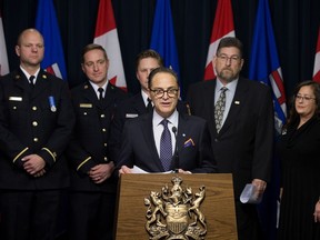 Surrounded by firefighters, a retired paramedic, and a registered nurse, Finance Minister Joe Ceci announces new proposed governance for public sector pensions at the Alberta legislature in Edmonton on Tuesday, Nov. 20, 2018.