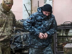 A Russian FSB security service officer escorts a detained Ukrainian sailor to a courthouse in Simferopol, Crimea, on November 27, 2018. - A court in Russian-annexed Crimea on November 27, 2018 ordered three Ukrainian sailors to be held in custody for two months after a weekend confrontation at sea with Russian border guards. Several others of the more than 20 Ukrainian sailors held by Russia were expected to appear before the court later Tuesday.