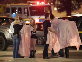 People comfort each other near the scene Thursday, Nov. 8, 2018, in Thousand Oaks, Calif. where a gunman opened fire Wednesday inside a country dance bar crowded with hundreds of people on "college night."