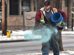 Alex Hussey spreads salt onto the sidewalks along 100 Ave. near 115 St. in central Edmonton after freezing rain fell in the morning on Nov. 9, 2018.