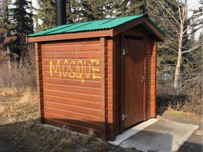 An Edmonton resident stopped to cover the word "mosque" spray painted on a Parks Canada outhouse near Jasper on Wednesday, April 19, 2017. Statistics Canada said hate-motivated property crimes like vandalism were in part responsible for a nationwide 47 per cent increase in hate crimes last year.