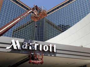 FILE - In this Tuesday, April 30, 2013, file photo, a man works on a new Marriott sign in front of the former Peabody Hotel in Little Rock, Ark.  Marriott says the information of up to 500 million guests at its Starwood hotels has been compromised. It said Friday, Nov. 30, 2018,  that there was a breach of its database in September, but also found out through an investigation that there has been unauthorized access to the Starwood network since 2014.