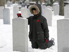 Eight-year-old Joaquin Biasbas, a Grade 3 student from St. John Bosco School, places a poppy on a headstone at the No Stone Left Alone ceremony held at Beechmount Cemetery in Edmonton on Monday, Nov. 5, 2018. Poppies were placed on all of the headstones in the Cemetery's field of honour by military members and local Edmonton students.