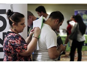 FILE- In this Jan. 30, 2018, file photo, Loredana Gonzalez, of Doral, Fla., fills out a job application at a JobNewsUSA job fair in Miami Lakes, Fla. On Friday, Nov. 2, the U.S. government issues the October jobs report.