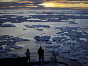 In this July 21, 2017 file photo, researchers look out from the Finnish icebreaker MSV Nordica as the sun sets over sea ice floating on the Victoria Strait along the Northwest Passage in the Canadian Arctic Archipelago.