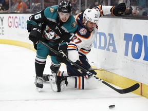Anaheim Ducks' Josh Mahura, left, and Edmonton Oilers' Milan Lucic fight for the puck during the first period of an NHL hockey game Friday, Nov. 23, 2018, in Anaheim, Calif.