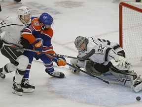Edmonton Oilers Jujhar Khaira is checked by Los Angeles Kings Austin Wagner (left) as he skates in on Kings goalie Jonathan Quick (right) during first period NHL hockey game action in Edmonton on Thursday November 29, 2018.