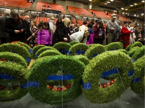 People inspect wreaths at the conclusion of the City of Edmonton Butterdome Remembrance Day Service on Saturday Nov. 11, 2017, in Edmonton.