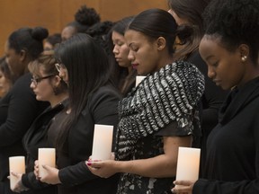 Students hold candles and take part in a moment of silence during a National Day of Remembrance and Action on Violence Against Women ceremony at NorQuest College, in Edmonton Thursday Dec. 6, 2018.