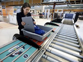 Canadian Air Transport Security Authority (CATSA) spokeswoman Christine Langlois demonstrates the new CATSA Plus security screening system at the Edmonton international Airport in Edmonton on Friday, Dec. 7, 2018. The new system allows four passengers to load their carry-on baggage for security screening at the same time.