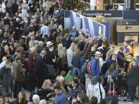 People wait near the departures gate at Gatwick airport, near London, as the airport remains closed with incoming flights delayed or diverted to other airports, after drones were spotted over the airfield last night and this morning, Thursday, Dec. 20, 2018.