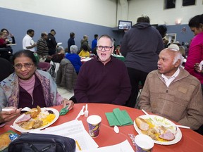 Millbourne Community Life Centre site-director Tim Cook, middle, speaks with Angie Bhatti, left, and her husband Pastor Patras Bhatti of the Multicultural Alliance Church. All are part of the eclectic mix of community members who now use a building that used to be a church. They're gathered here for a community Christmas dinner on Dec. 15, 2018 in Edmonton.