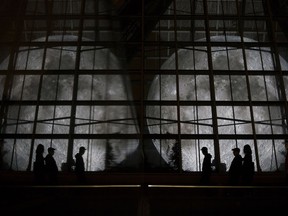 A reflection creates the illusion of two Moons as Edmontonians check out the Museum of the Moon exhibit at the Muttart Conservatory, in Edmonton Saturday Aug. 25, 2018.