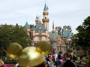 In this Jan. 22, 2015, file photo, visitors walk toward Sleeping Beauty's Castle in the background at Disneyland Resort in Anaheim, Calif.