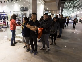 M.J. Borresin, left, her husband Kim, middle, and friend J.R. Denia, right, wait to get into a store in the Premium Outlet Collection at the Edmonton International Airport on Wednesday, Dec. 26, 2018.