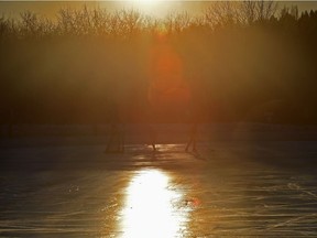 Two skaters playing some pickup hockey as the sun sets behind the trees at Hawrelak Park in Edmonton, December 17, 2018.