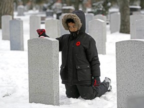 Joaquin Biasbas (8-years-old), a grade three student from St. John Bosco School, places a poppy on a headstone at the No Stone Left Alone ceremony held at Beechmount Cemetery in Edmonton on Monday November 5, 2018. (PHOTO BY LARRY WONG/POSTMEDIA)