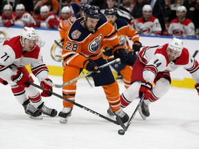 The Edmonton Oilers' Kyle Brodziak (28) battles the Carolina Hurricanes' Lucas Wallmark (71) and Calvin de Haan (44) during first period NHL action at Rogers Place in Edmonton on Sunday, Jan. 20, 2019.