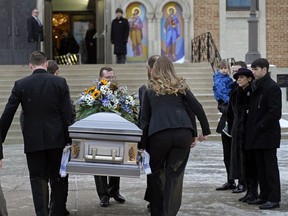 The family of Gene Zwozdesky stand at right while the casket is carried outside the Ukrainian Orthodox Cathedral of St. John in Edmonton where a funeral was held on Wednesday, Jan. 16, 2019.