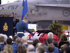 Fellow pilot and friend to Capt. Thomas McQueen, Capt. Jordan Rychlo, touches his casket after delivering the eulogy at the funeral service at the Warplane Heritage Museum in Hamilton, Ont. on Wednesday, December 7, 2016. Capt. McQueen died when the CF-18 he was piloting crashed during a training mission at CFB Cold Lake on Nov. 27, 2016.