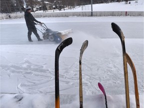 Nick Bevington sweeps the snow off the Cloverdale Community ice rink in Edmonton on Wednesday, Dec. 26, 2018.