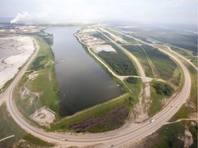 A highway loops around a tailings pond at the Syncrude facility as seen from a helicopter tour of the oil sands near Fort McMurray, Alta., on July 10, 2012. Syncrude has agreed to plead guilty and pay $2.75 million in fines over the deaths of 31 great blue herons at its Mildred Lake oilsands mine north of Fort McMurray. The birds were found dead or dying in 2015 near a pump house at an abandoned sump pond.