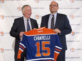 Edmonton Oilers CEO Bob Nicholson, left, and new President and General Manager Peter Chiarelli hold up an Oilers jersey with Chiarelli's name on it during a press conference in Edmonton on Friday April 24, 2015.