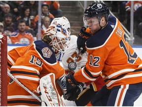 Calgary Flames' Sean Monahan (23) and Edmonton Oilers' Colby Cave (12) battle in front as goalie Mikko Koskinen (19) makes the save during first period NHL action in Edmonton on Saturday, Jan. 19, 2019.