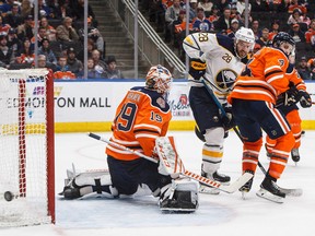 Buffalo Sabres forward Zemgus Girgensons and Edmonton Oilers defenceman Kris Russell  battle in front as goalie Mikko Koskinen makes the save on Jan. 14, 2019, during NHL action in Edmonton.