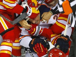 Edmonton Oilers Milan Lucic is tangled up with Calgary Flames in NHL hockey action at the Scotiabank Saddledome in Calgary on Nov. 17, 2018.