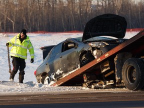 An Edmonton Police Service officer helps cleanup as a Toyota Corolla involved in a fatal single vehicle crash off the eastbound lanes of Anthony Henday Drive is towed west of the Manning Drive off ramp in Edmonton on Thursday, Feb. 21, 2019.