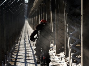 A cyclist in winter gear rides along the multiuse path on a cold day on the High Level Bridge in Edmonton, on Monday, Feb. 25, 2019. Photo by Ian Kucerak/Postmedia