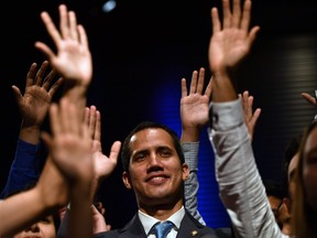 Venezuela's National Assembly head and self-proclaimed acting president Juan Guaido (C) raises his hands surrounded by students after speaking at the Metropolitan University in Caracas, on February 11, 2019. - Opposition chief Juan Guaido, now recognized by 50 countries as Venezuela's interim president, will lead a rally on Tuesday as he steps up pressure on beleaguered President Nicolas Maduro and tries to force the military to back down and allow in the aid.