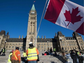 Men wear a yellow vests and wave the Canadian flag on Parliament Hill before the planned  Convoy for Canada truck protest in Ottawa, Ontario, on February 19, 2019.