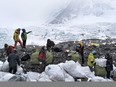 In this May 8, 2017, file photo released by Xinhua News Agency, people collect garbage at the north slope of the Mount Qomolangma in southwest China's Tibet Autonomous Region. China announced Monday, Jan. 21, 2019 that it plans to cut the number of climbers attempting to scale Mount Everest from the north by 1/3 this year as part of plans for a major cleanup on the world's highest peak.