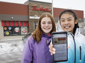 Mya Chau, right, 12, and Eve Helman, 12, who are digitally petitioning Tim Hortons to make the Roll up the Rim to Win campaign more environmentally friendly, are seen outside a Tim Hortons in Calgary on Feb. 3, 2019.