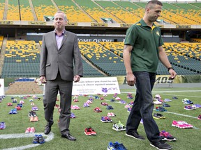 Eskimo president and CEO Len Rhodes, left, and quarterback Mike Reilly wrap up a photo shoot for a footwear donation at Commonwealth Stadium in Edmonton on Oct. 8, 2014.