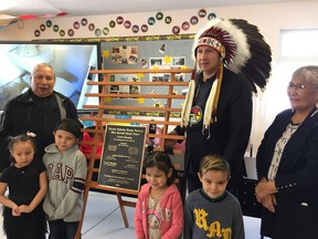 Members and children of the Alexis Nakota Sioux First Nation stand in front of a plaque commemorating the 20th anniversary of the Mne Koodi Head Start program on Tuesday, Feb. 5, 2019.