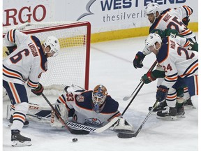 Edmonton Oilers' Adam Larsson, left, and Brad Malone, right, assist goalie Cam Talbot as Minnesota Wild's Zach Parise, in middle at right, can't reach the rebound during the first period of an NHL hockey game Thursday, Feb. 7, 2019 in St. Paul, Minn.